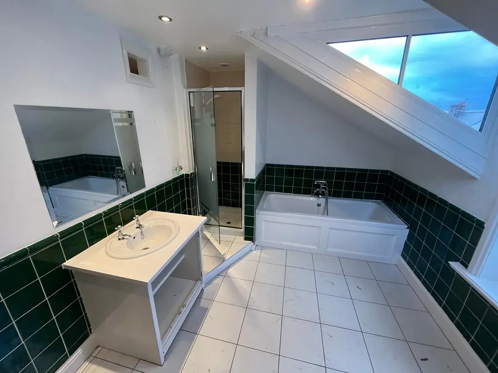 Before: attic bathroom with dated dark green tiles and old white suite under the sloped ceiling