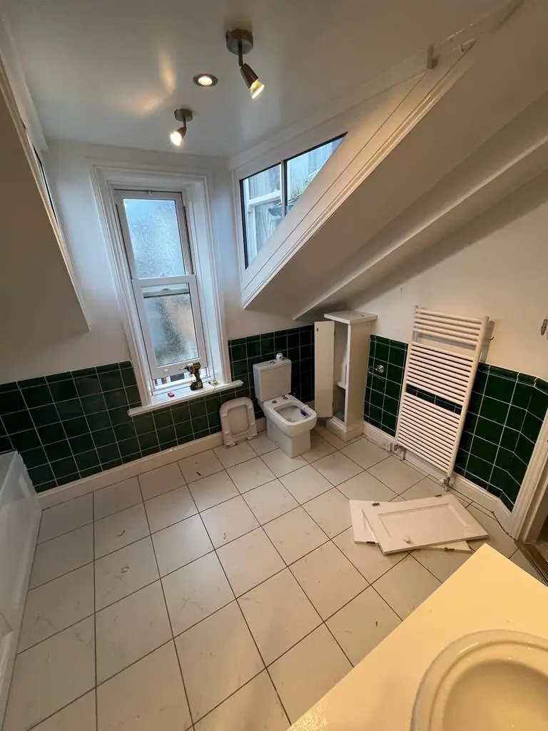 Before: old toilet, towel radiator and green half-tiled walls in the attic bathroom