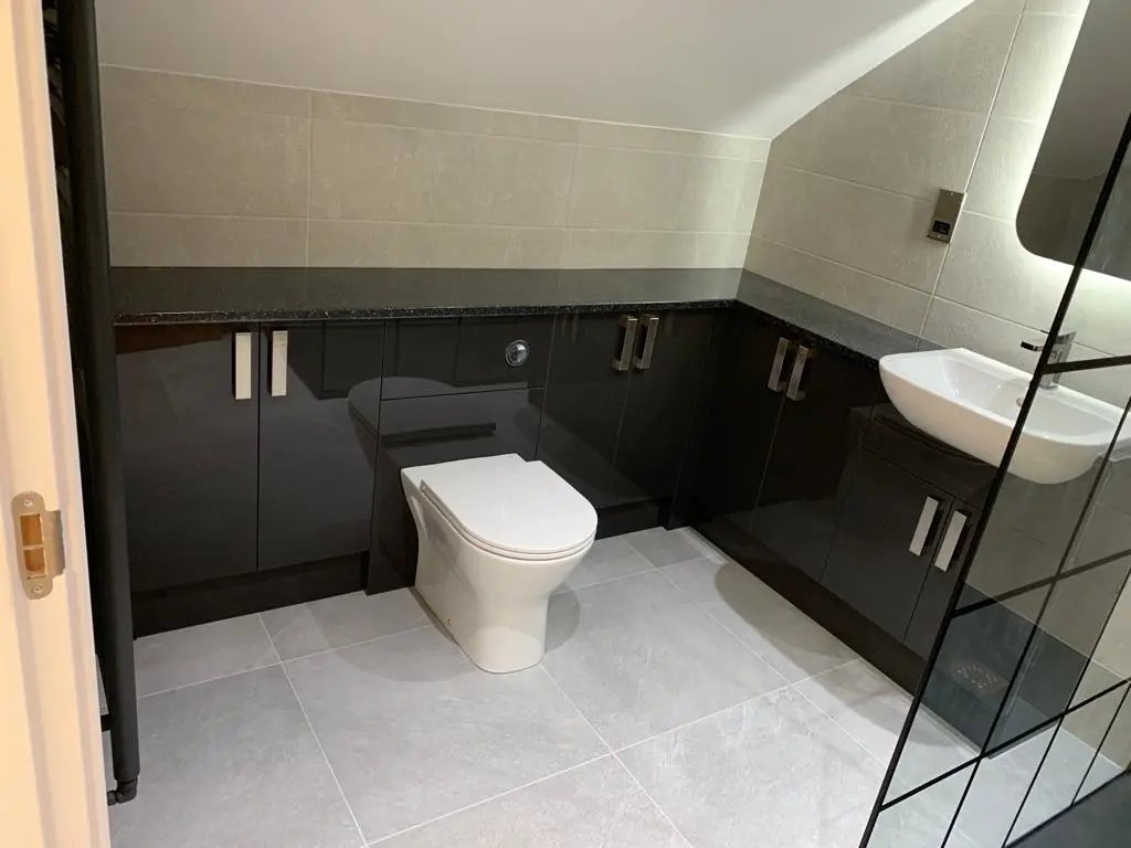 Black gloss fitted bathroom furniture with sparkle quartz top, built around the sloped eaves