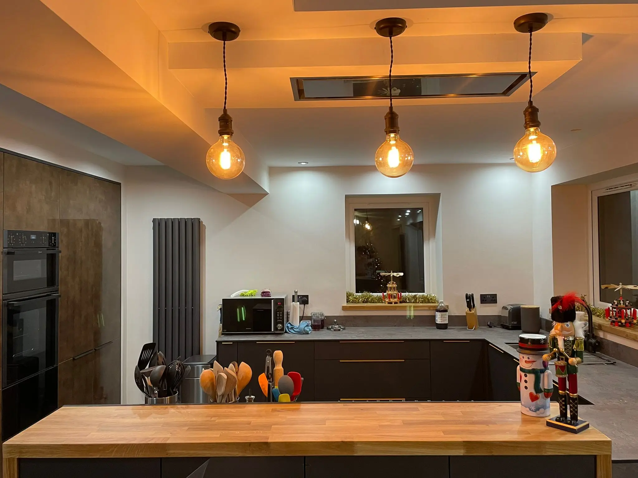 Charcoal kitchen with brass handles, exposed-filament pendant lights and oak worktop accents