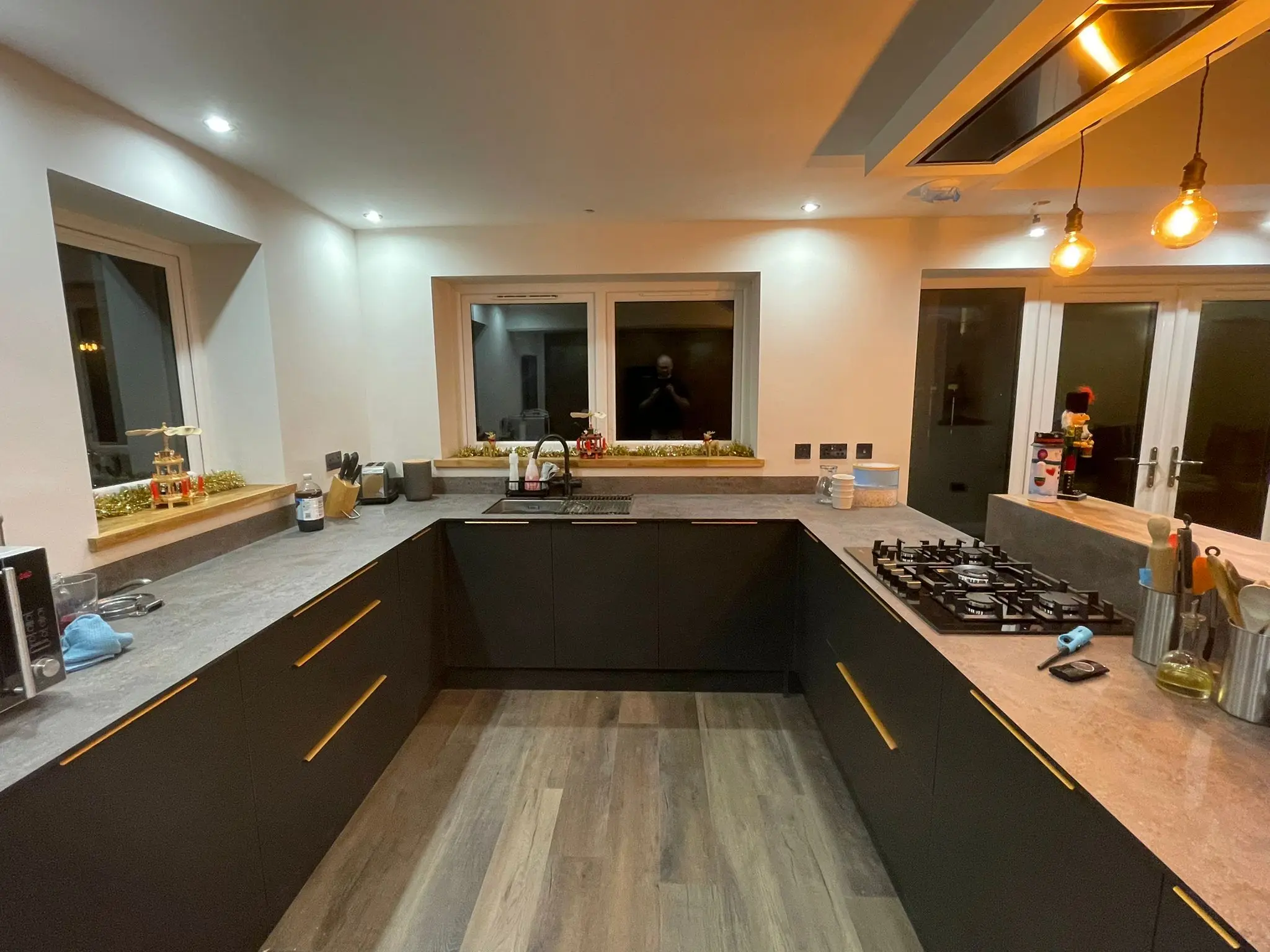 U-shaped charcoal kitchen with marble-effect quartz, five-burner gas hob and grey wood floor
