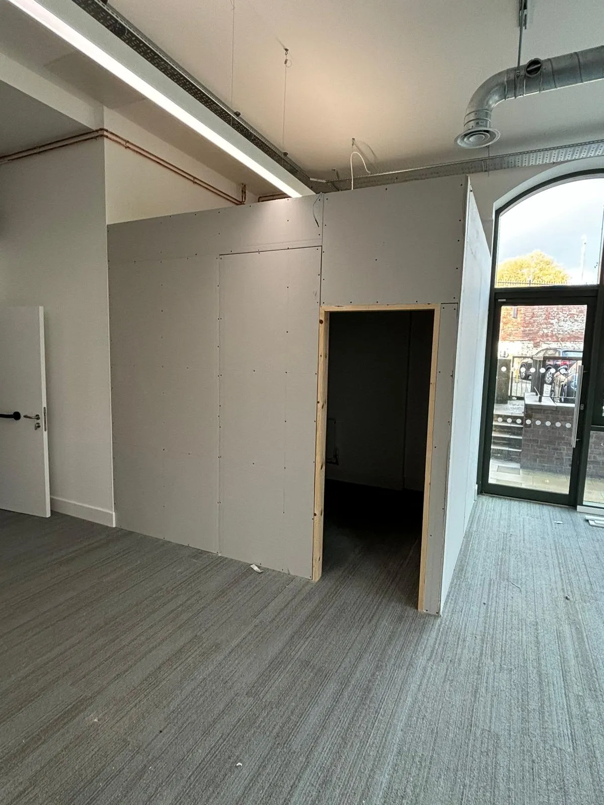 Commercial fit-out with new stud partitions beside an original arched warehouse window