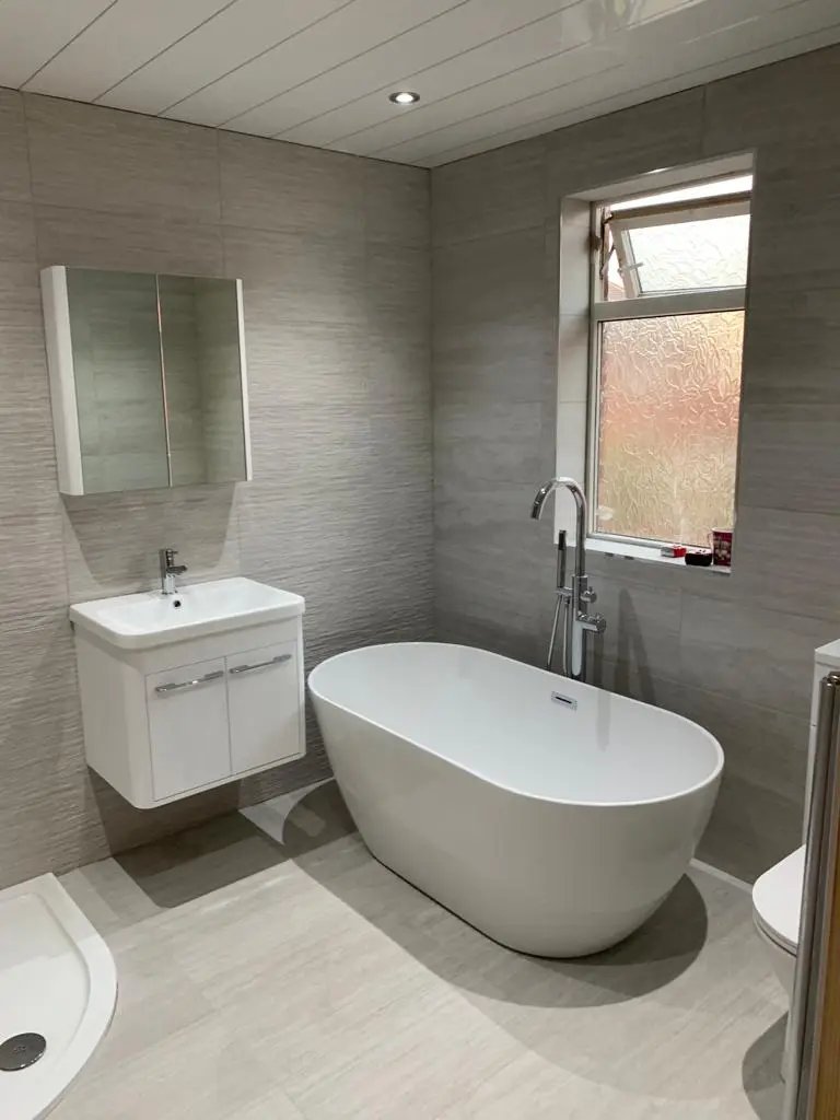 Freestanding oval bath with chrome floor-standing mixer against wood-grain grey porcelain walls