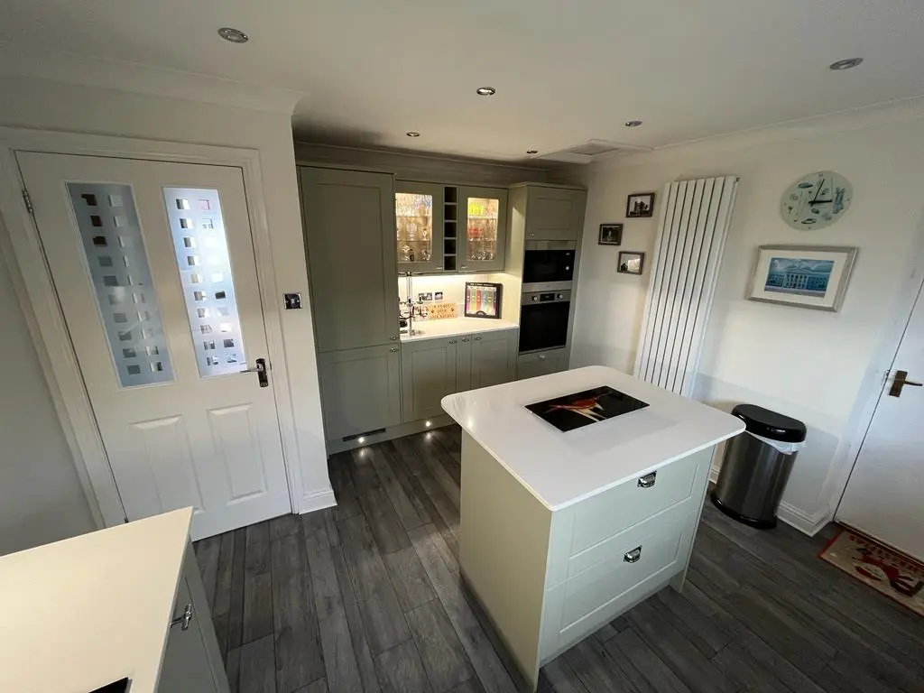 Kitchen island facing a glazed dresser unit with internal cabinet lighting