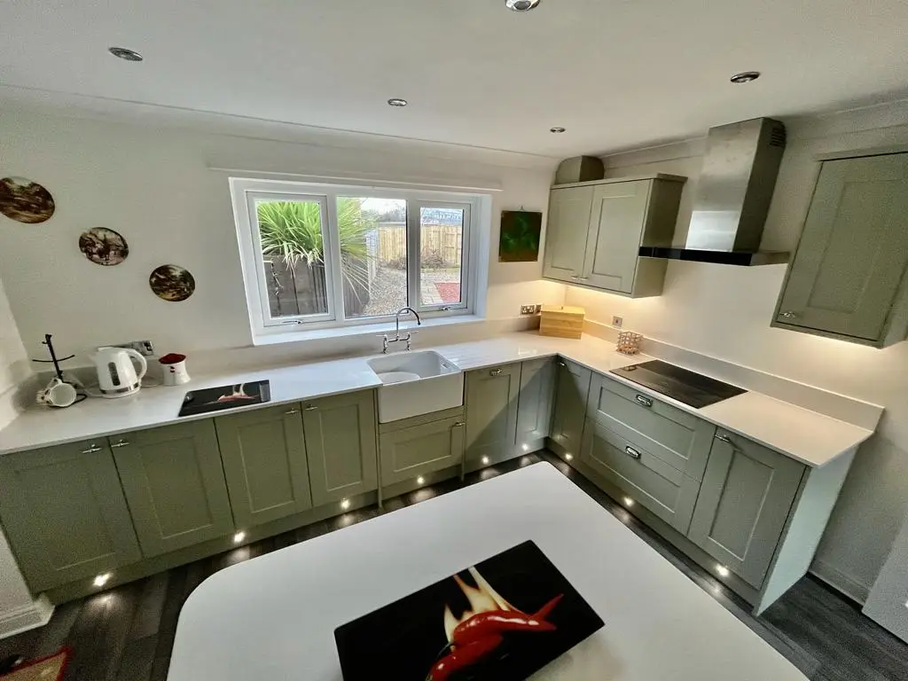 Sage green shaker kitchen with white quartz worktops, Belfast sink and garden window