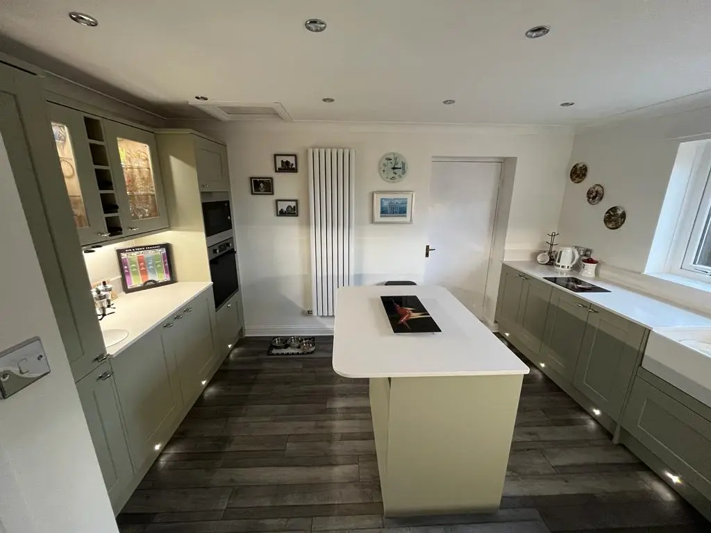 Sage shaker kitchen with island, white vertical radiator and dark wood floor