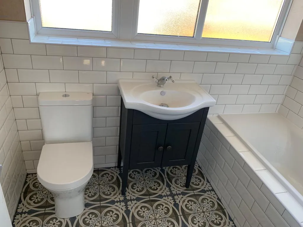 Traditional bathroom with patterned encaustic-style floor, navy vanity and Victorian-style basin