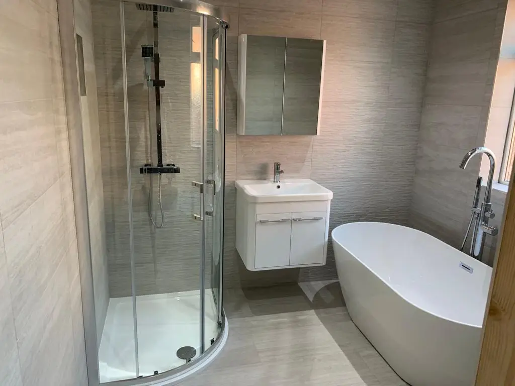Wall-hung white vanity and mirror cabinet beside the quadrant shower and freestanding bath