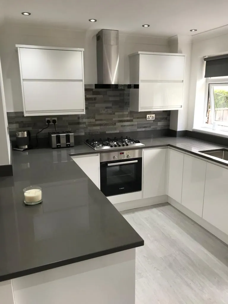 White gloss kitchen with wraparound grey quartz worktop and stainless chimney hood